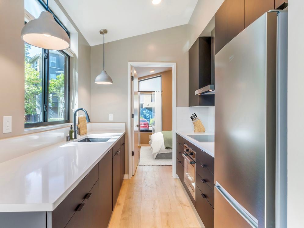 Freestanding home kitchen with stainless steel appliances, white quartz countertops, black cabinetry, and hard surface flooring