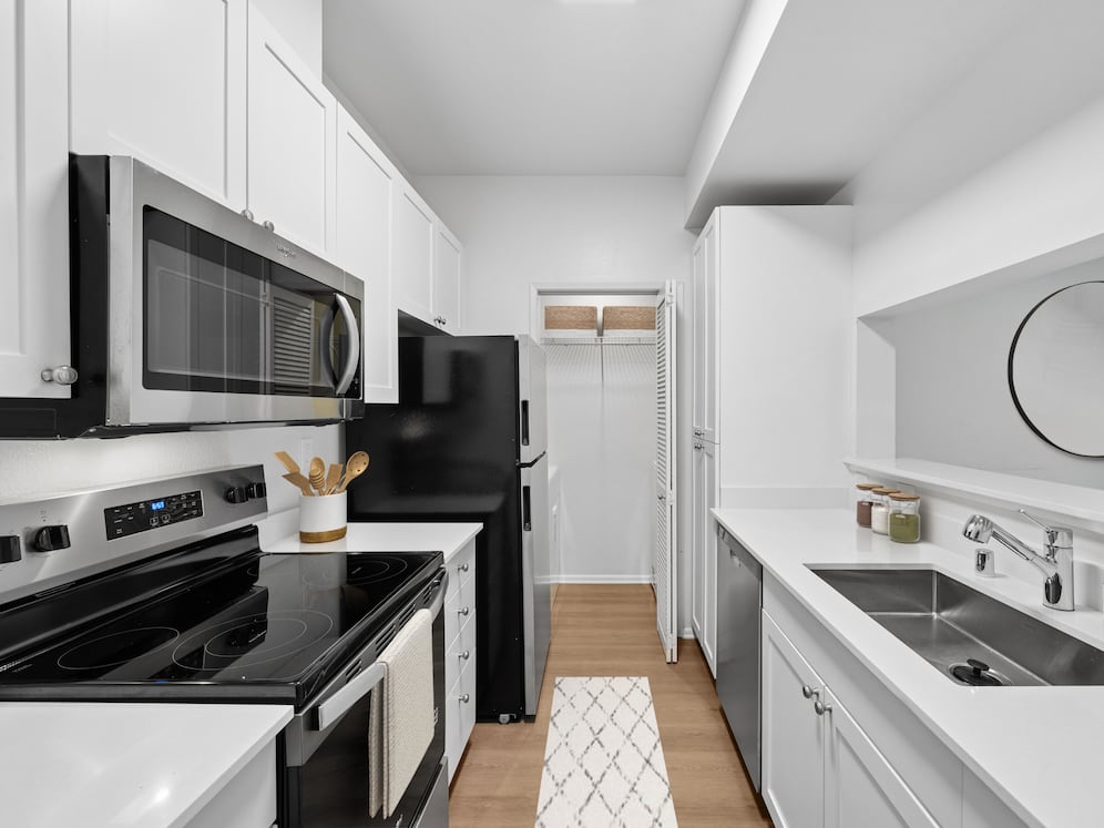 Renovated Package I kitchen with updated stainless steel appliances, white cabinetry, white quartz countertops, and hard surface flooring