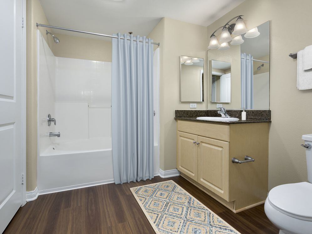 Classic Package I bath with brown speckled granite countertops, oak cabinetry, and hard surface flooring