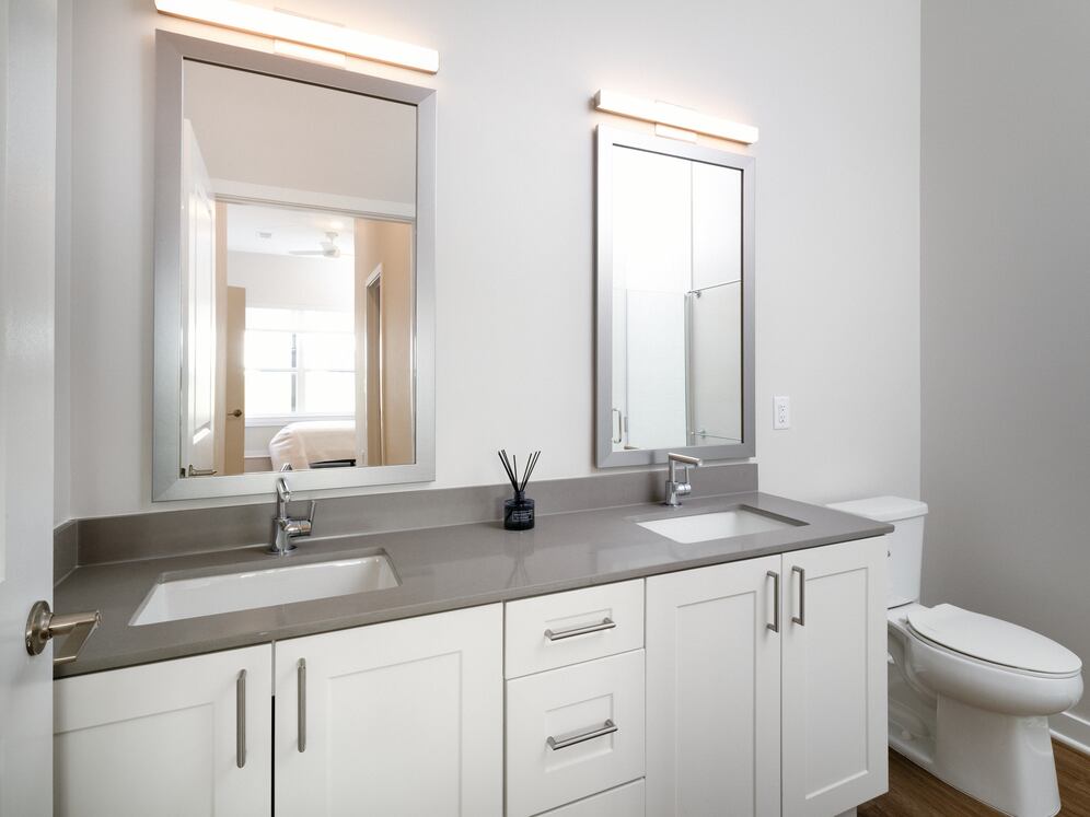 Upgrade Collection Primary bath with white shaker cabinetry, grey quartz countertops, and hard-surface vinyl plank flooring