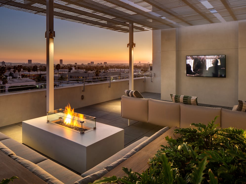Roofdeck at dusk with outdoor fireplace, flatscreen television, lounge seating and panoramic views
