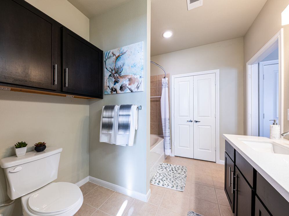 Baths with dark cabinetry, white quartz countertops, and hard surface flooring