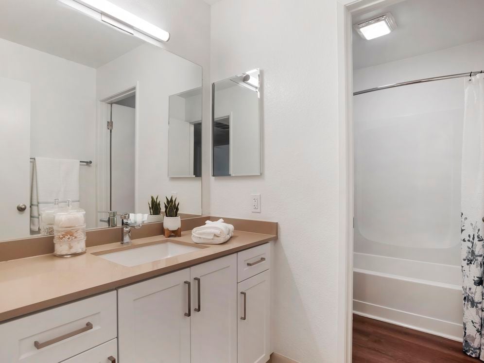 Baths with beige quartz countertops and white cabinetry