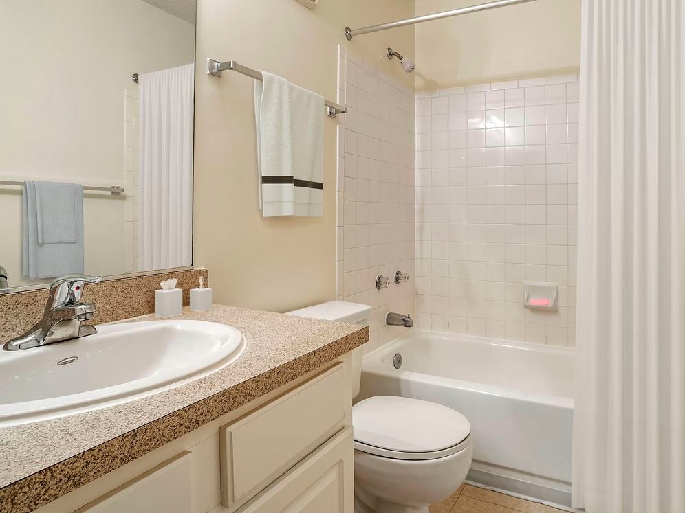Classic Package bathroom with laminate countertop, white cabinetry and tile flooring