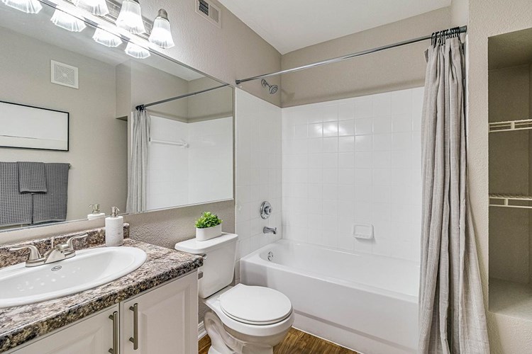 Bright bathrooms featuring wood-style flooring, granite-style counter tops and large mirrors.