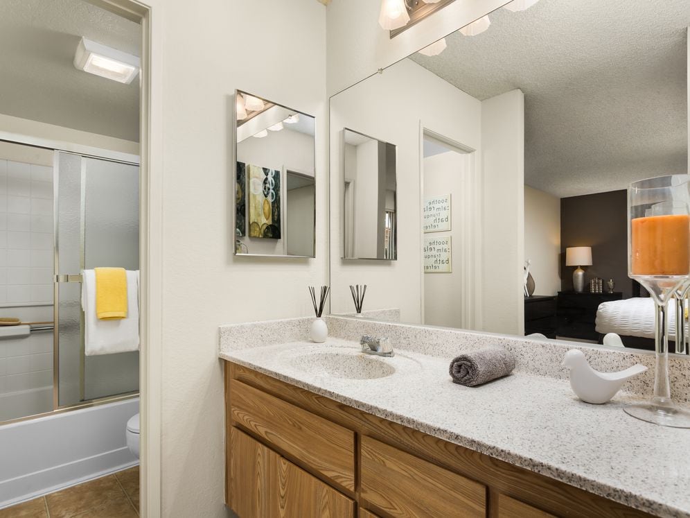 Classic Package bath with oak cabinetry, white speckled granite countertop, and tile flooring