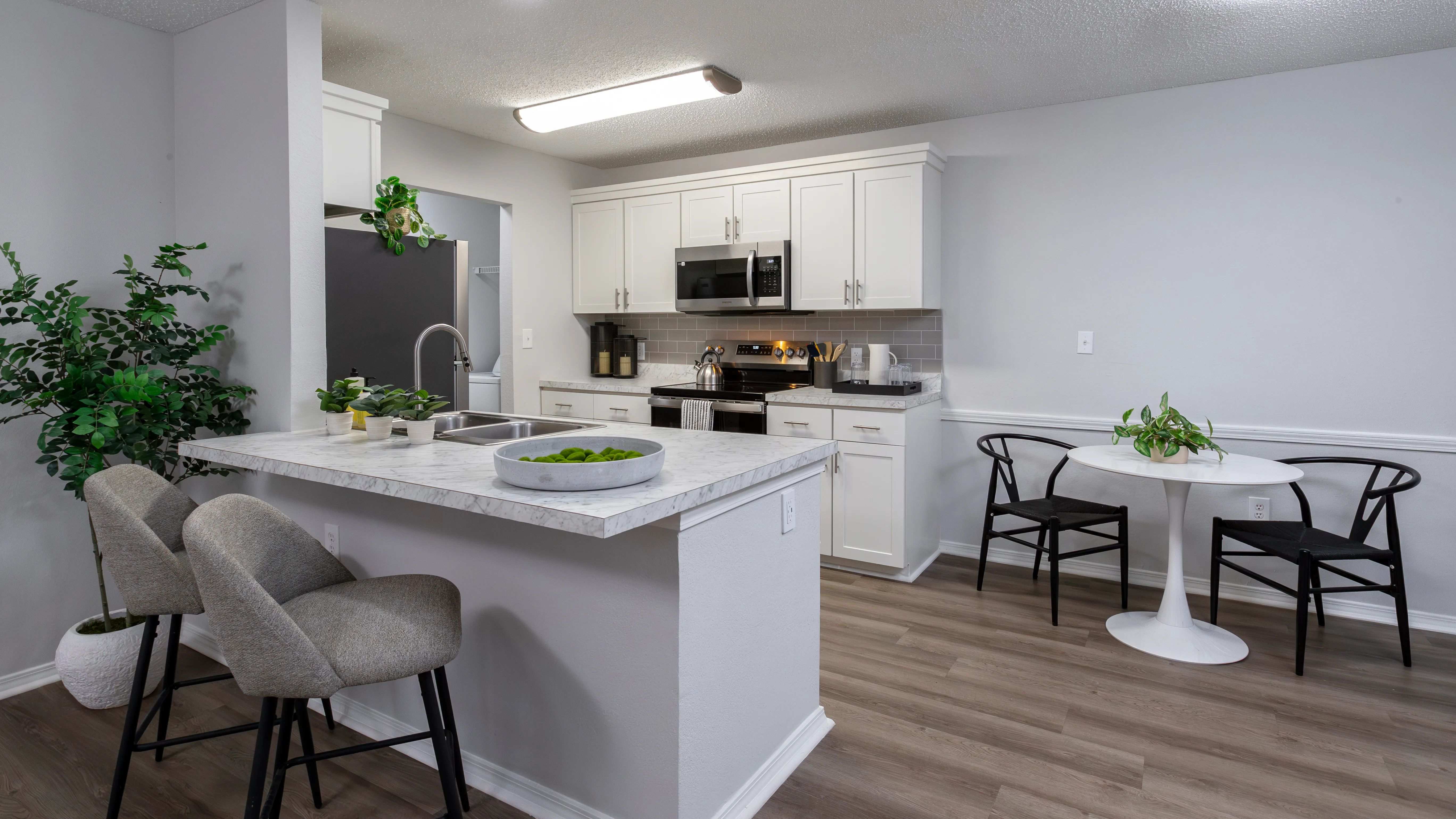Enjoy the contemporary design of this kitchen featuring a breakfast bar, stainless steel appliances, and a comfortable dining area.